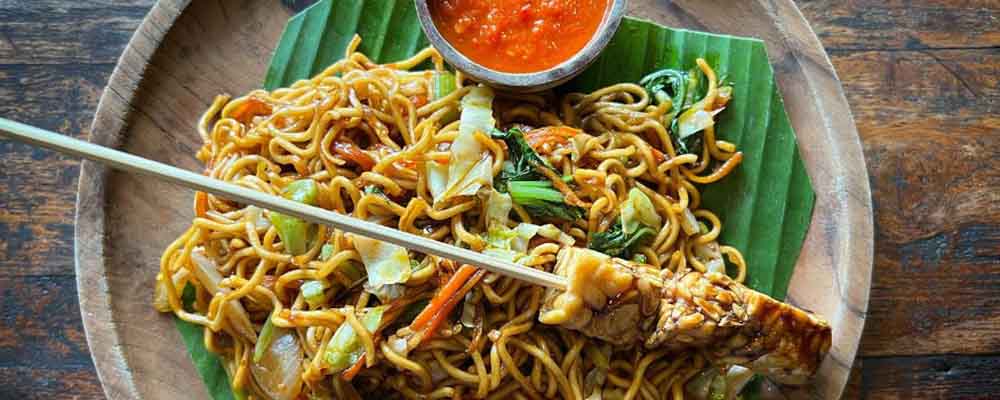 Noodle dish in a bowl with a chicken skewer